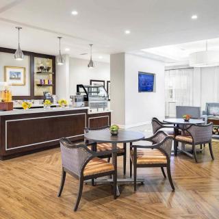 A modern lounge area with a cafe setup, featuring wooden flooring and stylish seating arrangements.