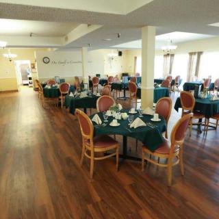 A spacious dining area with neatly set tables and chairs on a wooden floor.
