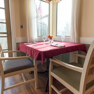 Cozy dining area with a table set for two near bright windows.