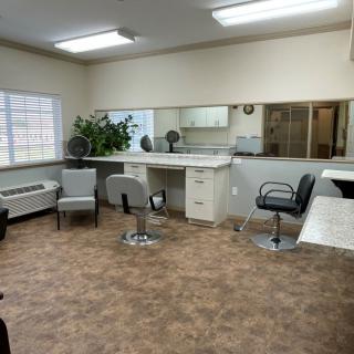 An empty hair salon with chairs, mirrors, and bright lighting.