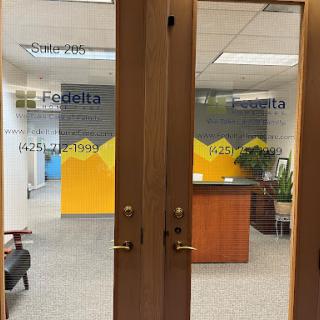 Entrance to a modern office featuring glass doors and a welcoming reception area.
