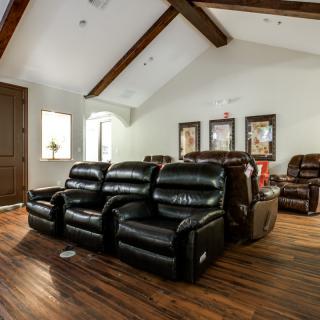 A cozy home theater with leather reclining chairs and a beamed ceiling.