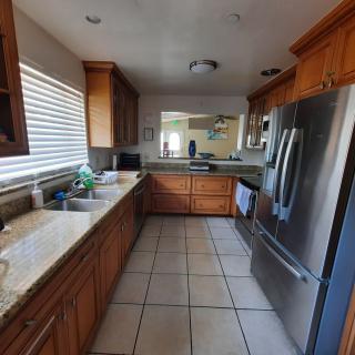 A modern kitchen with wood cabinets, stainless steel appliances, and a tiled floor.