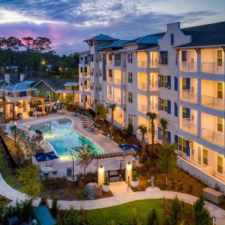 An illuminated apartment complex with a swimming pool at dusk.