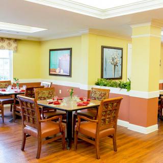 A well-lit dining area with wooden tables and chairs, featuring tasteful decor and artwork on the walls.