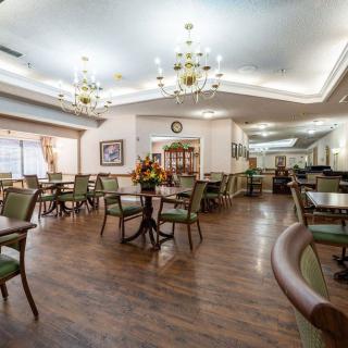 A cozy dining area with elegant chandeliers, wooden flooring, and neatly arranged tables and chairs.