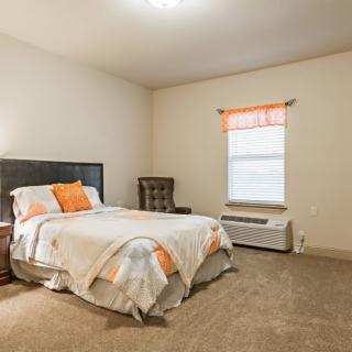 A cozy bedroom with a bed, chair, and window.