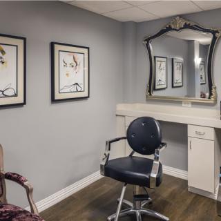 A stylish hair salon with a modern interior featuring a mirror, chair, and artwork on the walls.
