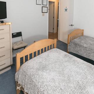 A cozy bedroom with two beds, a dresser, and a television.