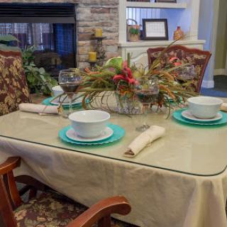 A beautifully set dining table with a cozy fireplace in the background, featuring elegant tableware and seasonal decorations.
