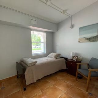A cozy room featuring a bed, chair, and natural light from the window.
