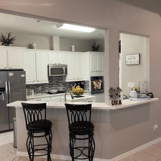 Modern kitchen interior with bar stools and white cabinetry.