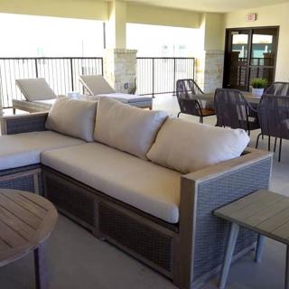 A comfortable outdoor patio setting featuring a large cushioned sofa and several lounge chairs.