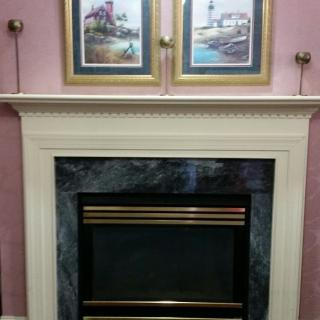 A traditional fireplace with a decorative mantel adorned with framed artwork.