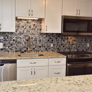 Modern kitchen with granite countertops and mosaic tile backsplash.