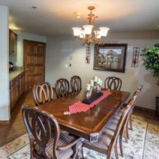 A well-decorated dining room featuring a wooden table and chairs, illuminated by a chandelier.