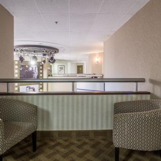 A cozy interior with two patterned chairs and a view of the hallway balcony.