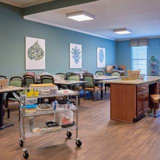 A well-organized classroom with tables, chairs, and a medical cart.