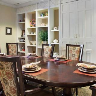 A cozy dining room with an elegantly set table and decorative shelving.