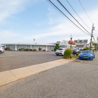 A parking lot with cars in front of a motel under a clear sky.