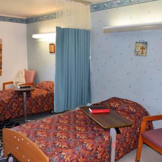 A shared hospital room with two beds separated by a curtain.