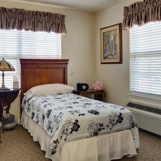 A cozy bedroom with a single bed, floral bedding, and window curtains.