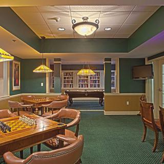 A cozy game room featuring a pool table, chess board, and comfortable leather seating.