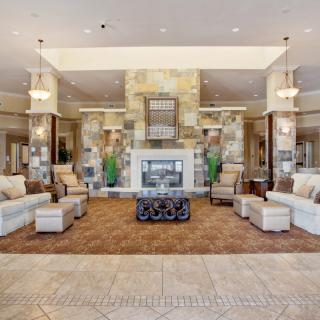 A spacious and elegantly decorated lobby featuring a central fireplace, comfortable seating, and stylish lighting.
