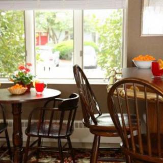 A cozy dining area with wooden tables and chairs, accented by natural light and plants.