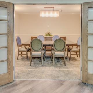 A well-appointed dining room with a large table and elegant chairs, accented by a chandelier above.