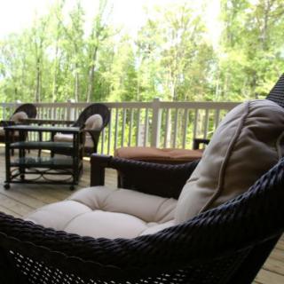 A cozy outdoor patio with wicker furniture surrounded by lush trees.