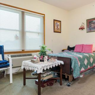 A cozy and well-decorated bedroom with a bed, side table, and large window.