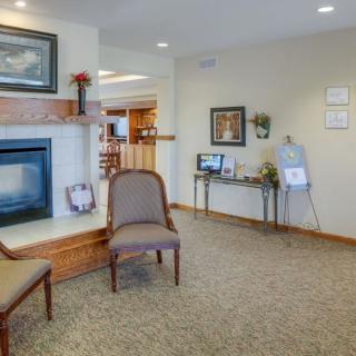 A cozy living room with a fireplace and chairs, decorated with artwork and home decor.