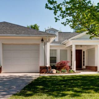 A suburban home with a garage and a driveway, surrounded by trees.