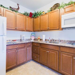 A kitchen with wooden cabinets, a countertop, and appliances including a microwave and a refrigerator.
