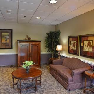 A cozy living room with a sofa, coffee table, and cabinet adorned with artwork and plants.