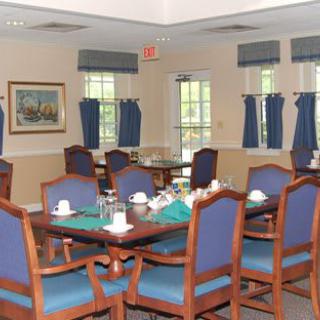 A cozy dining room with neatly arranged tables and chairs, featuring blue curtains on the windows.