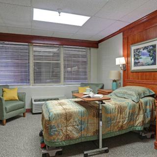 A cozy hospital room with a patient bed and comfortable seating.