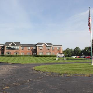 A view of a residential building with a flag in the foreground and well-maintained grass.