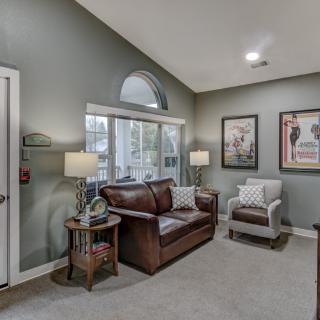 A cozy living room with a leather sofa, armchair, and decorative wall art.