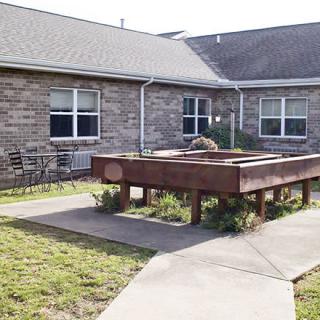 A courtyard featuring a raised garden bed and patio furniture surrounded by a brick building.