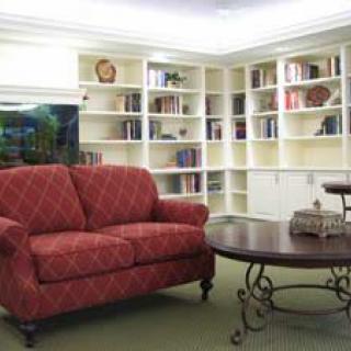 A cozy living room with a red sofa, bookshelves, and a wooden coffee table.