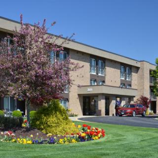 A well-maintained hotel exterior with vibrant flowers and lush greenery.