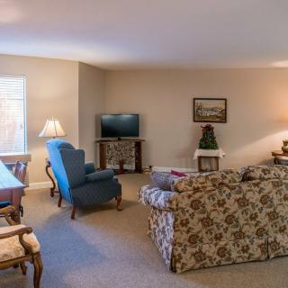 A cozy living room with a floral sofa, armchair, television, and warm lighting.