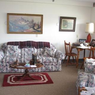 A cozy living room with a sofa, framed paintings, a lamp, and a small table.