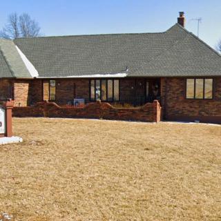 A one-story brick house with a large lawn and a chimney.