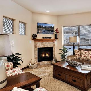 A cozy and well-decorated living room featuring a fireplace, comfortable furniture, and large windows.