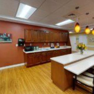 A modern kitchen with wooden cabinets, a large counter, and warm lighting.