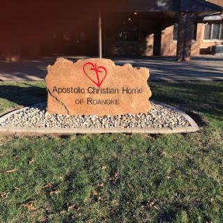 Sign for the Apostolic Christian Home, set in a landscaped area.