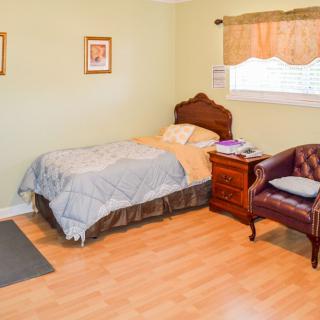 A cozy bedroom with a single bed, wooden furniture, and a window.